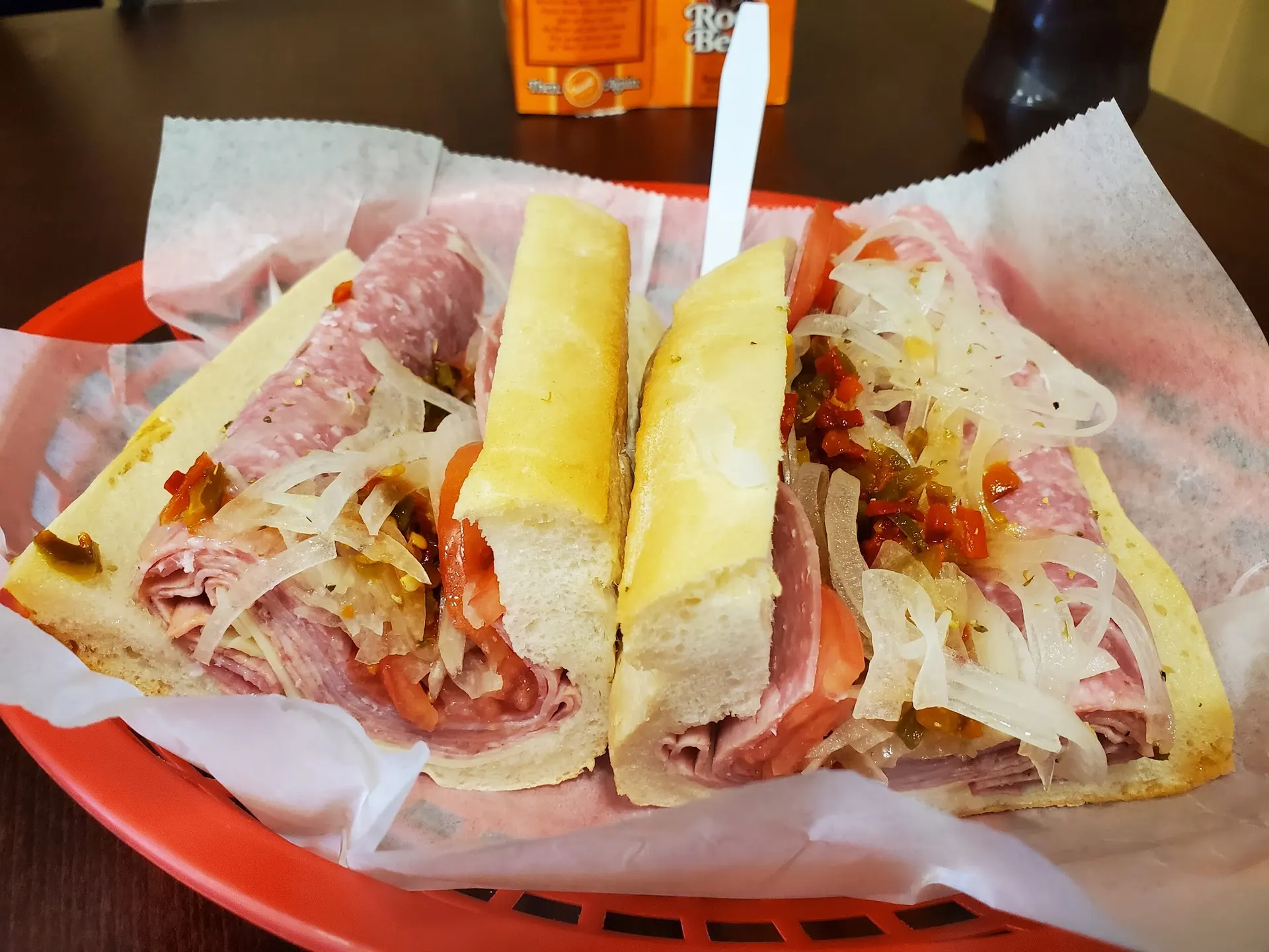 Pete's Italian sub piled with cold cuts, cheese, lettuce and tomato in a red basket